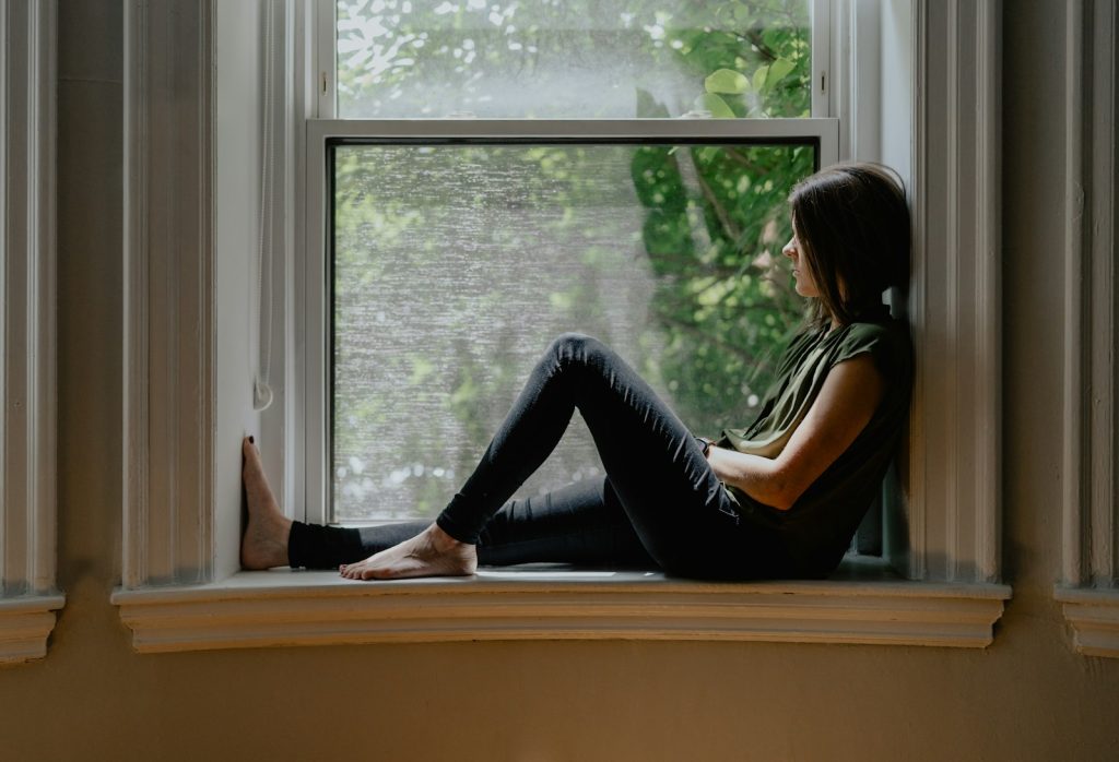 A woman sitting quietly by a window in soft morning light